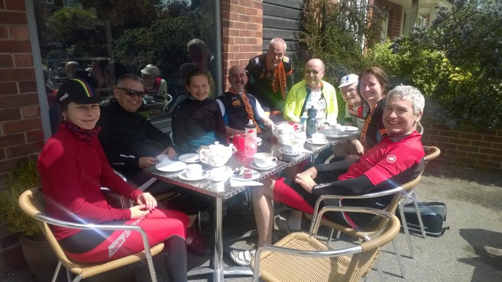 Photo of eight cyclists having coffee and cakes